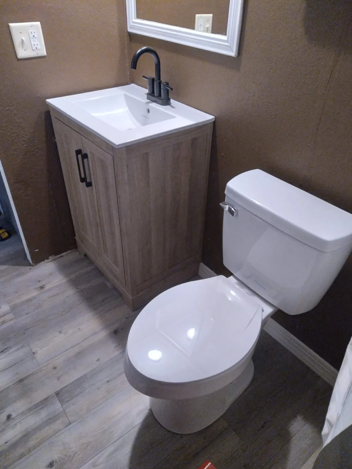 Finished bathroom with new vanity, toilet, and plank flooring